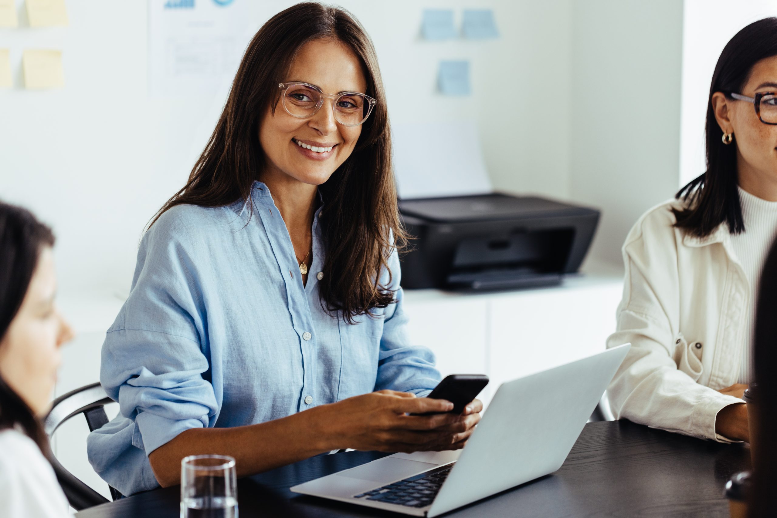 Business woman using a mobile phone in a meeting